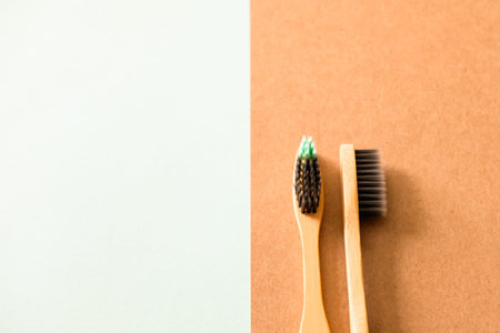 Zero waste self-care products. Natural bamboo toothbrush with charcoal bristles on green brown...