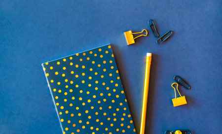 Notebook and cute golden pencils on trendy dark blue background. Flat lay minimalism style.