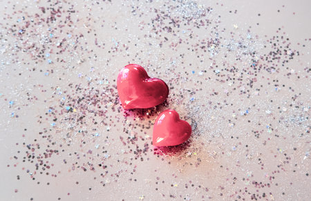 Red hearts and shiny hologram glitters on pastel background. Valentines day concept. 