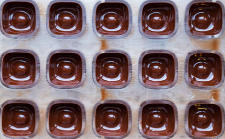 Dark chocolate molded pralines in the making on black background.の写真素材