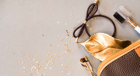 Cosmetic bag, eyelash curler, brow brush on shiny beige background. Beauty concept. Flat lay design.の写真素材
