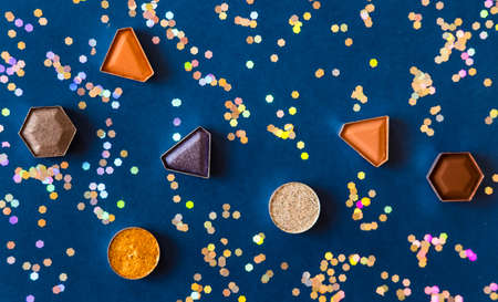Colorful eye shadows and golden glitters on dark blue background. Makeup products concept.の写真素材