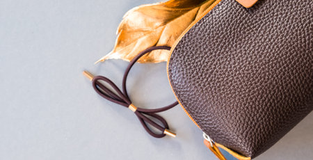 Brown cosmetic bag on shiny gray background. Beauty concept. Flat lay design.の写真素材