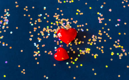Red hearts and shiny golden hologram glitters on dark blue background. Valentines day concept. の写真素材