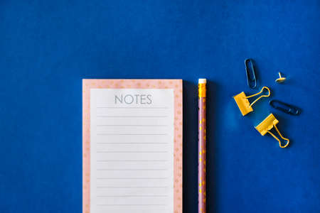 Pink notebook and cute golden pencils on trendy dark blue background. Flat lay minimalism style.の写真素材