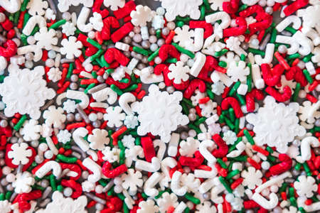 Christmas white snowflakes and red green sugar sprinkles on blue background. Flat lay style. Holiday trendy concept.の写真素材