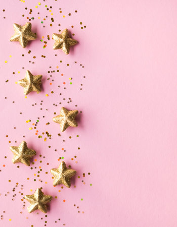 Golden stars glitter over pink background. Festive holiday backdrop.