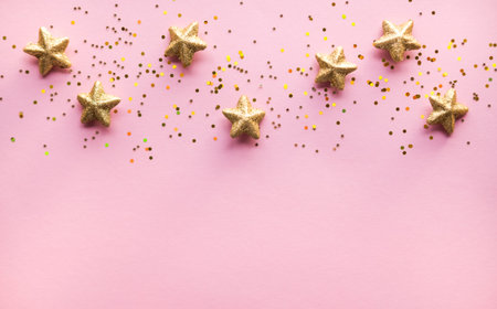 Golden stars glitter over pink background. Festive holiday backdrop.