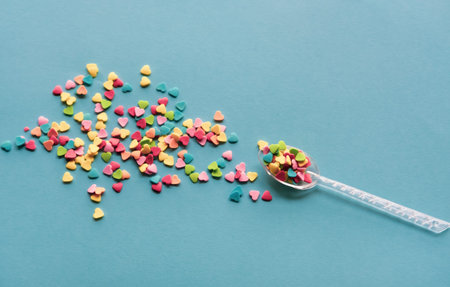 Colorful sugar heart shaped sprinkles on blue background. Valentines day concept. 