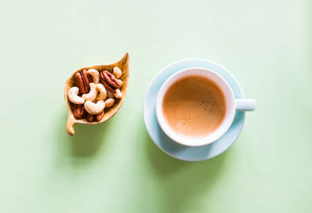 Cup of coffee espresso, nuts mix, and muesli on mint green background. Heathy breakfast concept.の写真素材