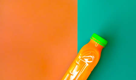 Bottle of carrot juice on vivid orange green background. Flat lay style.の写真素材
