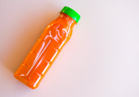 Bottle of carrot juice on white background. Flat lay style.