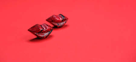 Red chocolate pralines in lips shape on vivid background banner, top view, selective focus.の写真素材