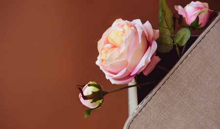 Artificial coral pink roses in textile gift box on chocolate brown background. Flat lay holidays...