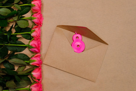 Pink roses and candle on light brown background. March 8 festive concept.
