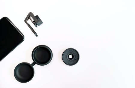 Black cellphone and macro lens, metal screw clip and silicon case on white background. Modern hobby concept.の写真素材