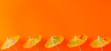 Orange paper cocktail umbrellas on vivid background. 