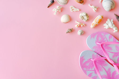 Trendy pink flip flops with palm trees print and seashells with corals on pastel background....
