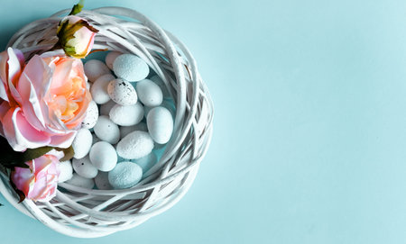 Creative Easter layout. White wooden wreath, pink textile roses and blue pastel eggs flat lay...