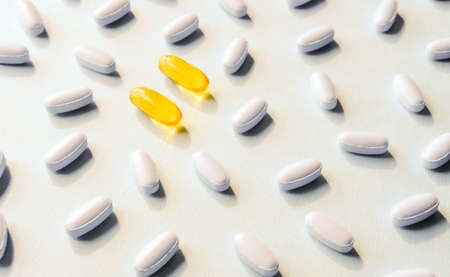 Yellow and white medicine pills and capsules on pastel background.の写真素材