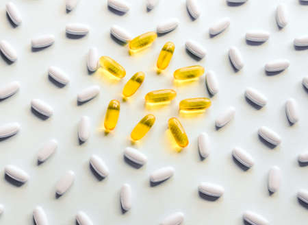 Yellow and white medicine pills and capsules on pastel background.の写真素材