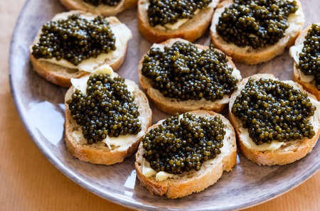 Natural sturgeon Black Caviar, butter and fresh baguette open sandwiches on gray plate.の写真素材