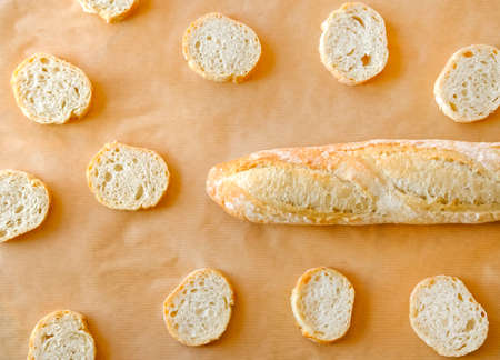Traditional fresh French baguette and crispy slices on brown natural background. の写真素材