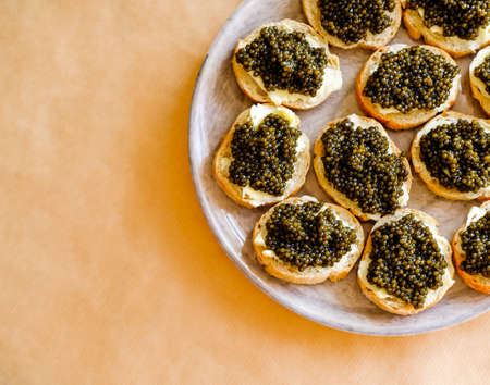 Natural sturgeon Black Caviar, butter and fresh baguette open sandwiches on gray plate.の写真素材