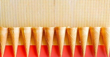 Empty ice cream cones on waffle and red background. Minimal food concept. の写真素材