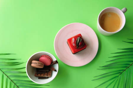 Macarons, chocolates, cake and coffee on green background. Sweet food concept. の写真素材