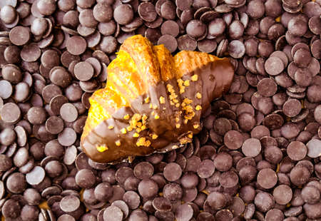 Classic croissant on dark chocolate couverture background. Sweet food design. の写真素材