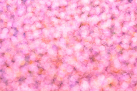 Abstract pink orange sparkler background, defocused lights. Festive concept. Selective focus.の写真素材