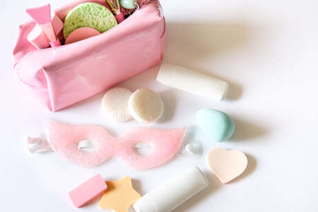 Pink cosmetic bag, beauty products, eye mask, mini soaps, silicon brushes, jade roller and different shapes sponges on white background. Skin care concept.の写真素材