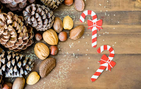 Christmas festive styled pine cones, nut mix and golden glitters background. Winter holidays concept. の写真素材