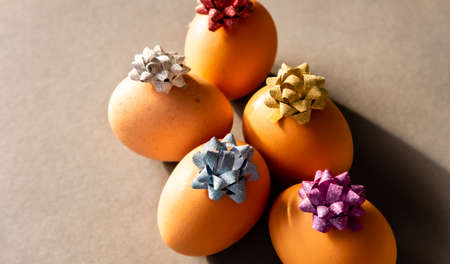 Brown Easter eggs with shiny cute bows on brown natural background. Holiday concept.の写真素材