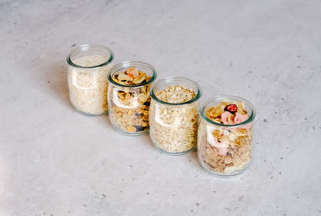Breakfast cereal ingredients in glass jars on gray marble background. Ready-to-eat fast food concept. の写真素材