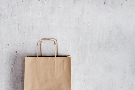 Brown Kraft paper shopping bag on light marble background. Minimal concept.の写真素材