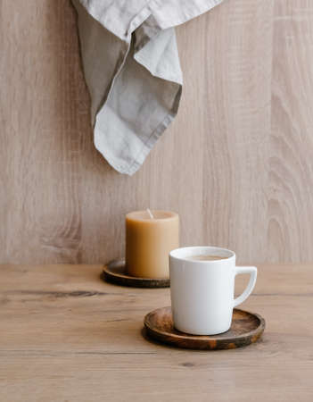 White cup of coffee and caramel candle on wooden background. の写真素材