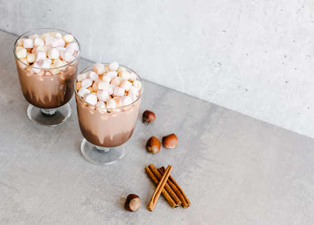Cocoa chocolate and milk drinks with mini marshmallows in tall glasses on gray background. Festive holidays food concept. の写真素材