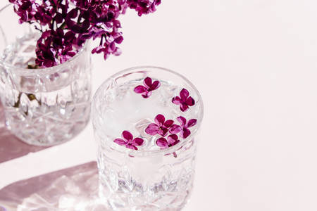 Beautiful vivid lilac flowers in crystal glass on pink background. の写真素材