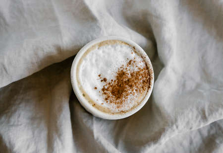 Cup of coffee cappuccino with cinnamon on natural linen background. Minimal food style.の写真素材