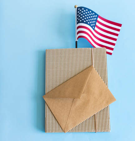 American flag and brown paper envelope on blue background.の写真素材