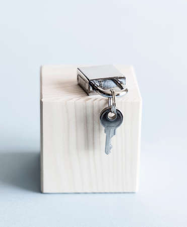Silver shiny metal padlock with keys on wooden stand and blue background.の写真素材