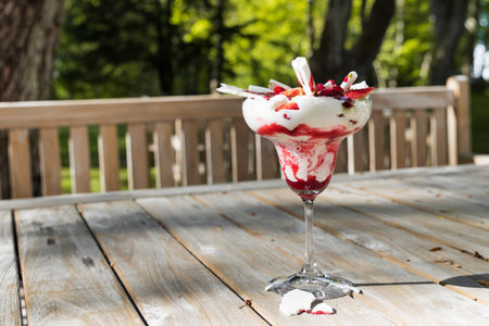 Traditional summer dessert Eton mess. Mixture of meringue, whipped cream, fresh strawberries and raspberries, decorated with mint sauce on wooden table background.の写真素材