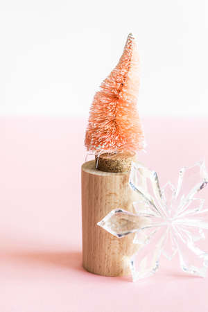Coconut fiber orange Christmas tree on wooden stand and snowflake on pink white background, zero waste festive concept.の写真素材