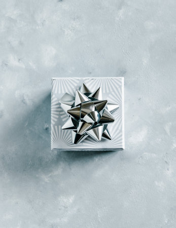 Christmas and New Year holiday monochrome background or greeting card. Gray gift box with silver...