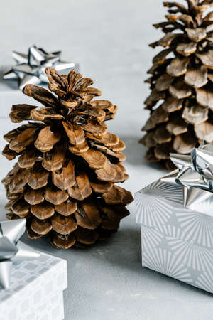 Christmas and New Year holiday background or greeting card. Gray gift boxes with silver bows and pine cones.の写真素材