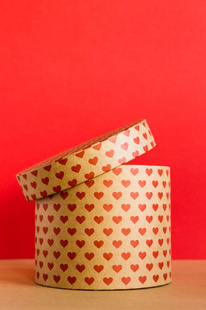 Valentines Day concept. Paper round gift box with hearts print on red background.