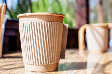 Disposable paper coffee cup with holder on table in cafe with wooden stirrer.Environmentally friendly lifestyle.Zero Waste,Save The Planet,Earth Day,No Plastic,Recycling Conceptの写真素材