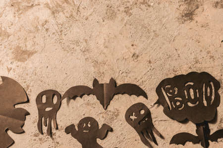 Figures from a black bat and ghosts carved from black paper on a concrete surface. copy space. Crafts for halloween celebration concept. Handwork. Flat layの写真素材
